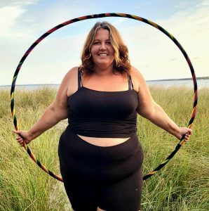 Abby standing near the beach with her beginner hoop.